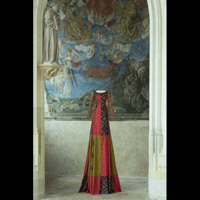 Series: Les Grand Robes Royales<br>
height: 3 m / 9 ft<br>
Installation in Fortresse Royale de Chinon, 2016-17<br>
A checkerboard surcoat of brilliant red bazin mixed with two different wax prints, one of which incorporates a fleur-de-lis motif, over a dress of yellow wax print with small floral patterns, overprinted with screen-print on the sleeves.<br>
Collaboration: Maxence Rapetti-Maus.