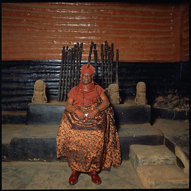 Adorned with beaded crown and tunic and a damask skirt, the Ero is seated in front of his paternal ancestral shrine. Fourth in rank among the Uzama, he guards the northwest entrance to the city of Urubi. His duties include ensuring the well-being of the Edaiken, or crown prince, and the Iyoba, or queen-mother, who live near him. <br>
Series: <i>Kings, Chiefs, and Women of Power</i><br>
Chromogenic print on Fujiflex Crystal Archive paper<br>
30” x 30”; Edition: 5 + 2 AP<br>
50” x 50”; Edition: 3 + 1 AP
