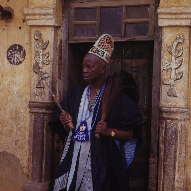 For the Yoruba people, the ancient city of Ile-Ife is the center of the universe and the origin of their traditions and beliefs. Chief Omisakin’s heavily embroidered garment, woven cap, blue beads, horse-tail fly whisk and ceremonial sword, and the plaque bearing his title, serve as emblems of his high status among other chiefs.