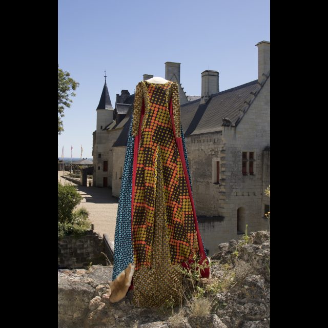 Series: Les Grand Robes Royales<br>
Height: 3 m / 9 ft<br>
Installation in Fortresse Royale de Chinon, 2016-17<br>
The dress is in wax print with patterns of spades, hearts, diamonds, and clubs; the surcoat has yellow circle motifs against a brown background, arranged into square panels by orange outlines. A cloak in purple and blue wax print is lined with red fabric and edged with red fox fur. <br>
Collaboration: Bouyahmed Zoulika, Toton Harumi, Richard Gaëlle, Fricard Anahit, Chaa Faiza, Malkhassian Soussana.